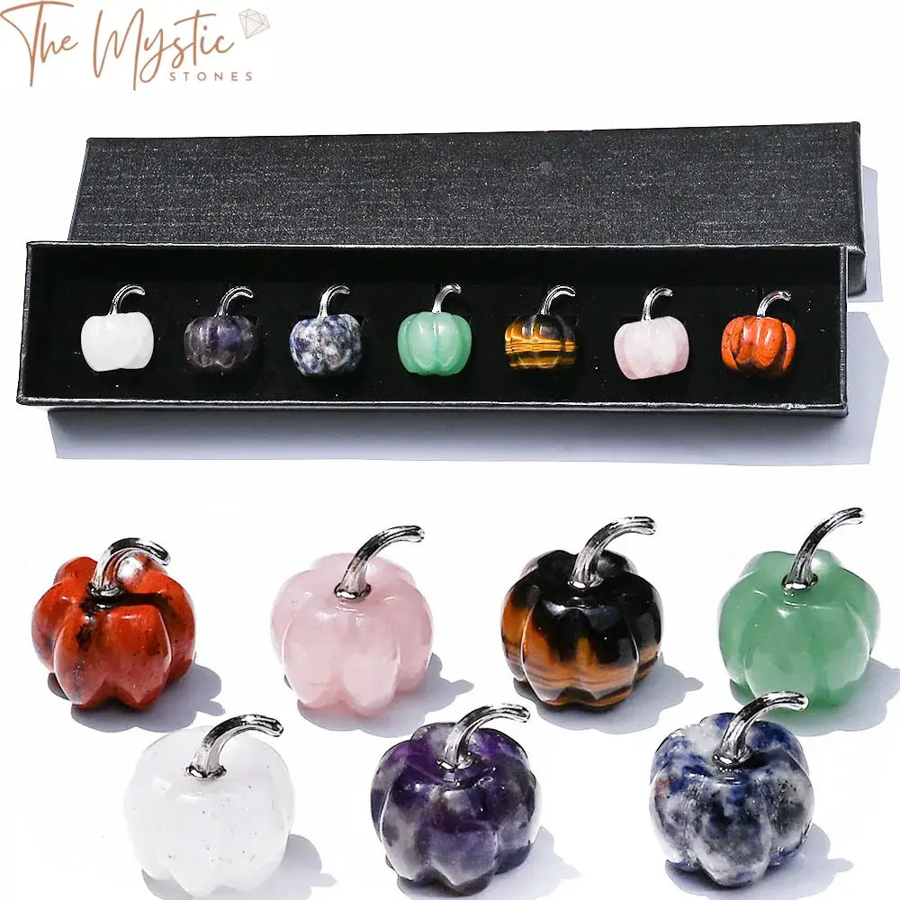 A set of small hand-carved gemstone pumpkins arranged neatly in a decorative gift box.