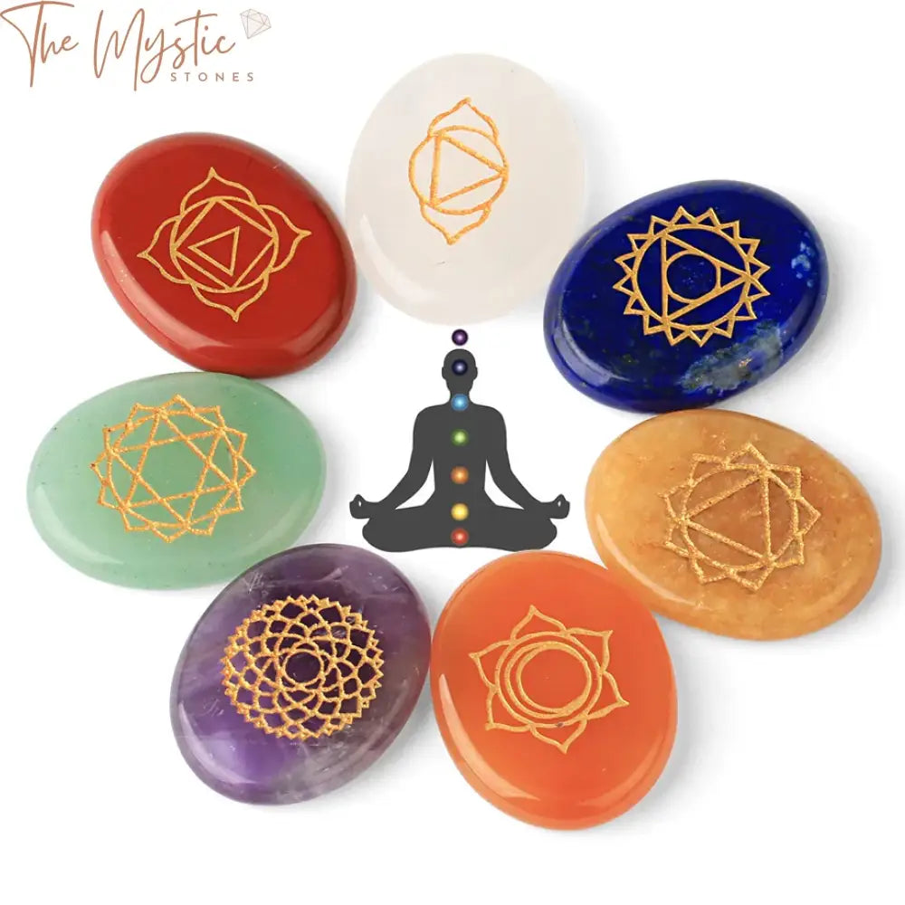 A set of seven chakra stones, each engraved with a corresponding chakra symbol, displayed in a row.