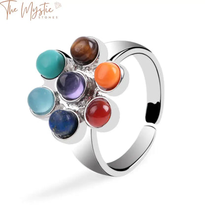 A close-up image of an adjustable rainbow ring featuring seven colorful chakra stones arranged in a flower pattern.