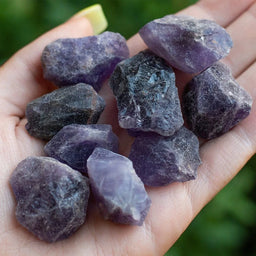 A collection of rough amethyst crystals with a variety of irregular shapes and sizes, displaying a vibrant purple hue.