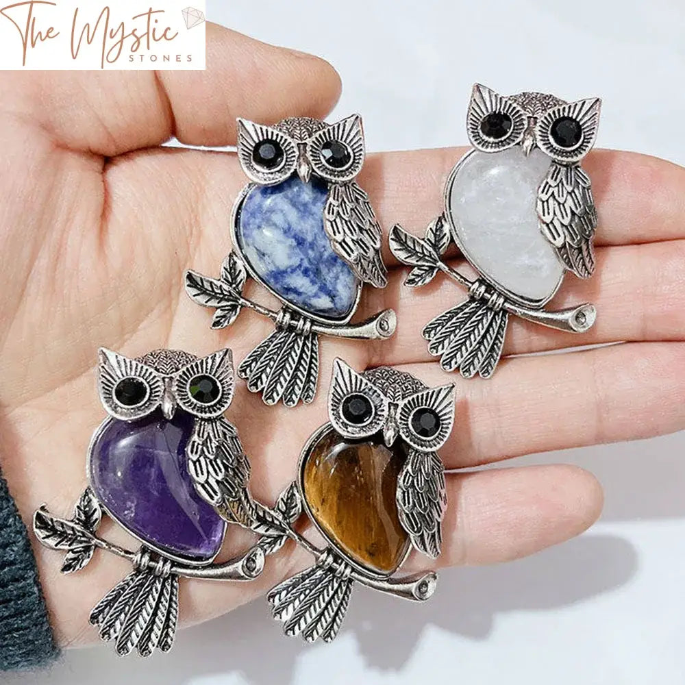 An intricate owl pendant made of alloy with natural stone inlays sits elegantly against a plain background.