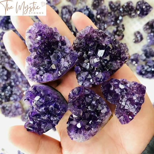 A natural amethyst quartz crystal cluster in the shape of a heart, showcasing vibrant purple hues and sparkling facets.