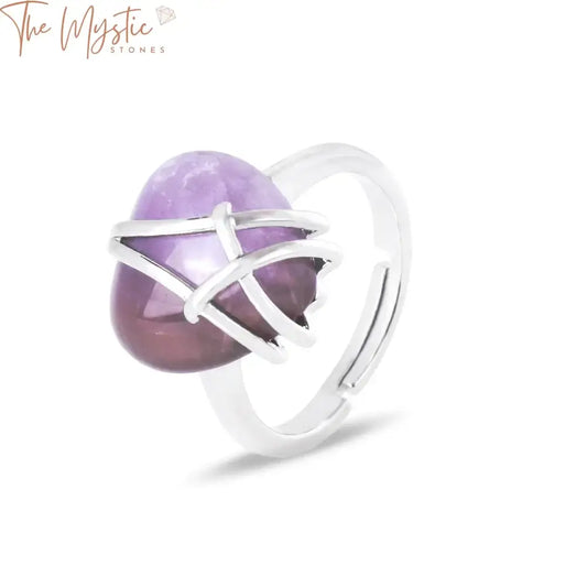 A silver-colored adjustable ring featuring a heart-shaped amethyst gemstone, intricately wrapped in wire.