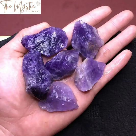 A collection of raw, rough-cut amethyst stones in various shades of purple, each measuring between 1 to 2 inches.