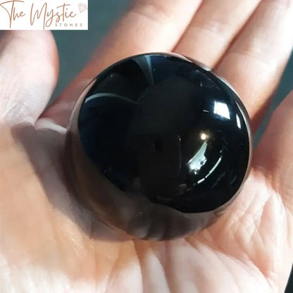 A polished 40mm black obsidian sphere with a smooth, glossy surface sits on a simple wooden stand.