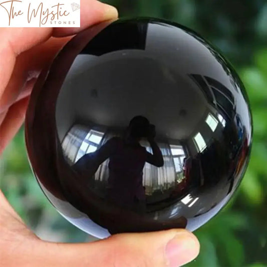 A smooth, glossy black obsidian sphere, approximately 20-60mm in diameter, crafted from natural Asian quartz crystal.