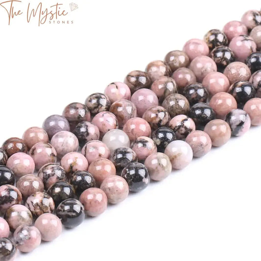 A close-up image of smooth, polished black line rhodonite beads, varying in shades of pink with dark veining patterns.