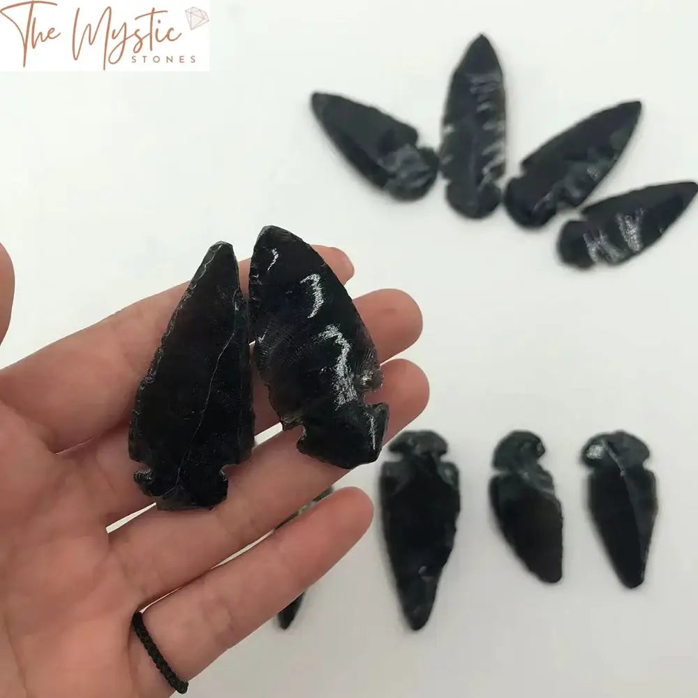 A collection of natural black obsidian arrowheads, intricately carved in an Indian style design.