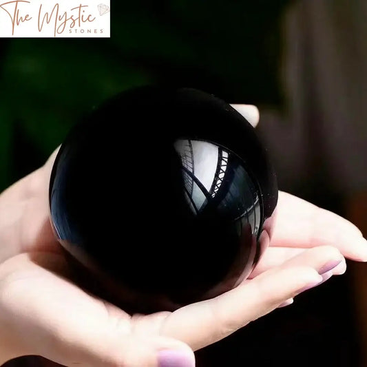 A polished 80mm black obsidian crystal sphere, reflecting light on its glossy surface.