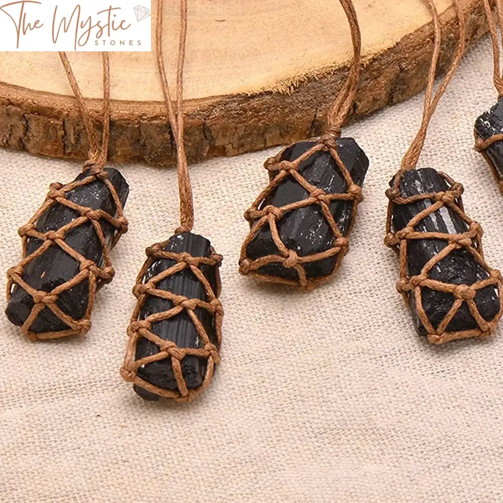 A natural black tourmaline stone with an irregular shape is wrapped in a braided rope, creating a pendant.