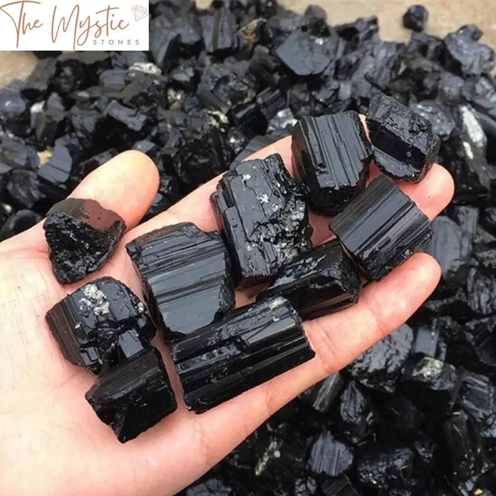 A collection of irregularly shaped black tourmaline raw crystals displayed on a wooden surface.