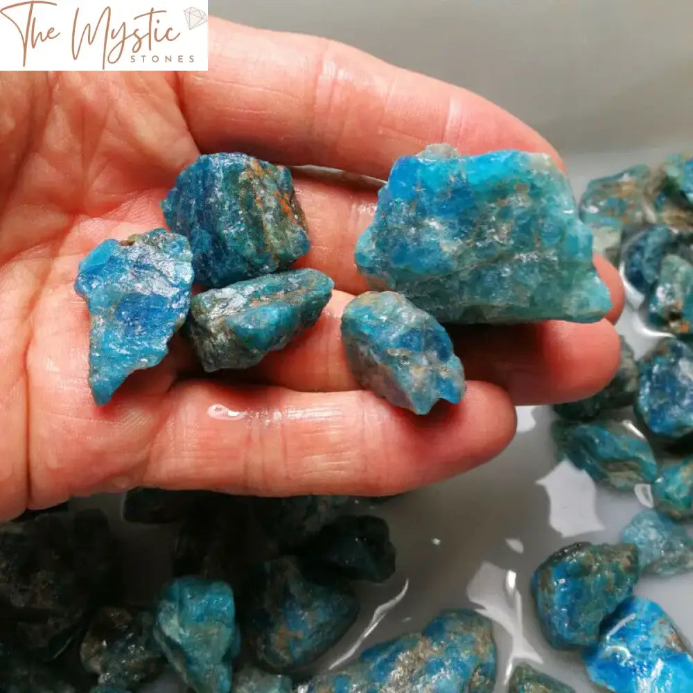 A collection of raw blue apatite crystal stones, varying in size and shape, shown as unpolished gravel.