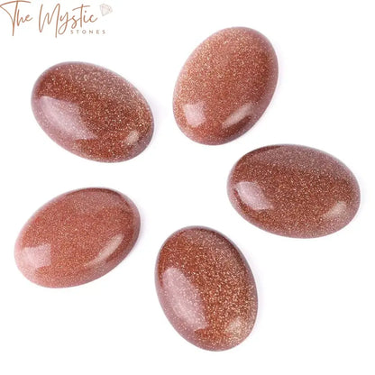 A collection of shiny brown sand cabochon beads, featuring an oval shape with a smooth, reflective surface.