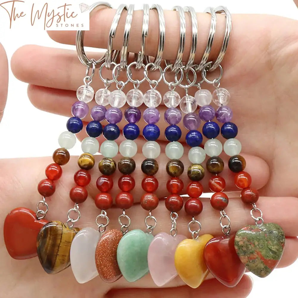 A keychain featuring a heart-shaped charm made of natural stones representing the seven chakras.