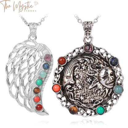 A silver-toned pendant necklace featuring a wing design with a row of seven colorful chakra crystals inlaid along the center.