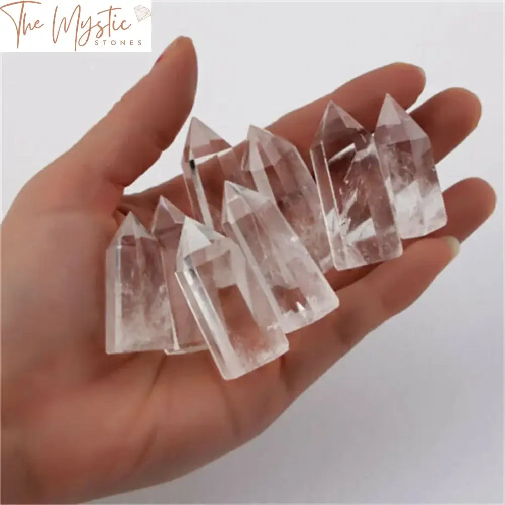 A clear quartz crystal wand point obelisk, approximately 30-40mm in height, stands vertically.