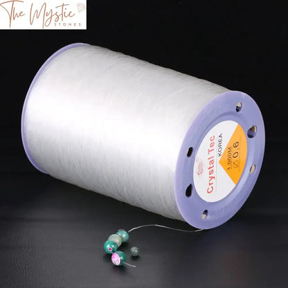 A spool of transparent elastic line labeled as "1000M Elastic Line Transparent Crystal Cord 1 Roll Stretch Thread.