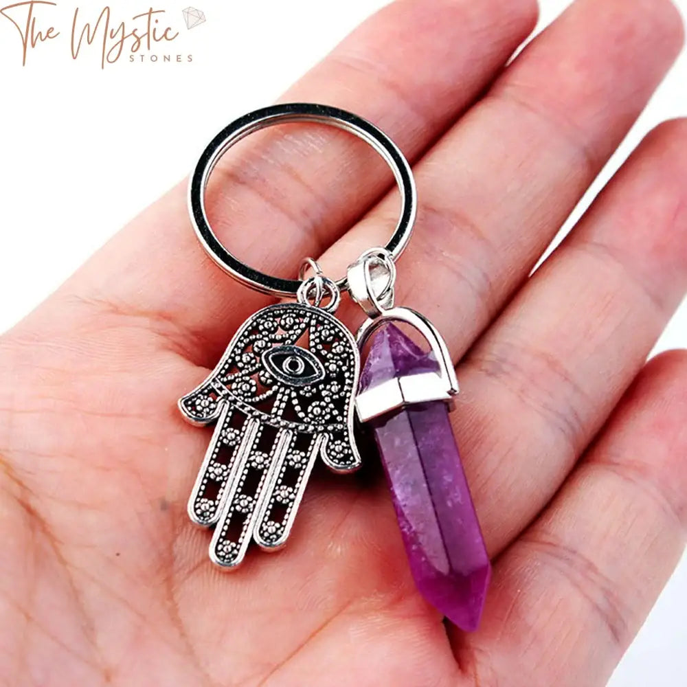 A keychain featuring a natural stone crystal point adorned with Hamsa Hand and Evil Eye charms.