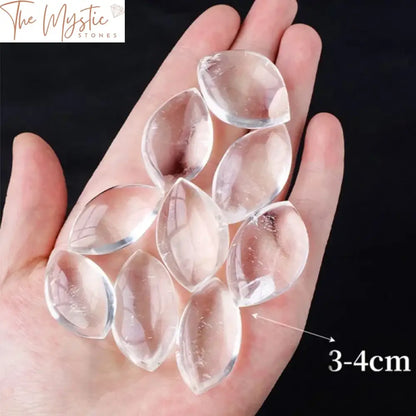 A collection of natural crystal clear quartz stones, each polished and shaped like a leaf, displayed together.