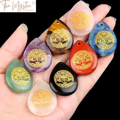 A collection of natural stone crystal pendants, each carved in a water drop shape, featuring the Tree of Life symbol.