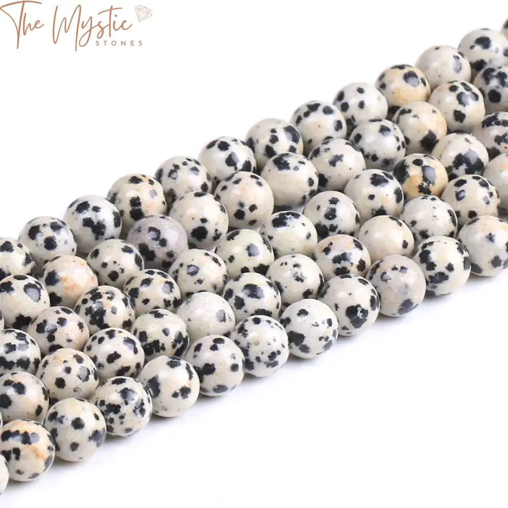 A collection of smooth, round natural Dalmatian stones featuring a white base with irregular black spots.