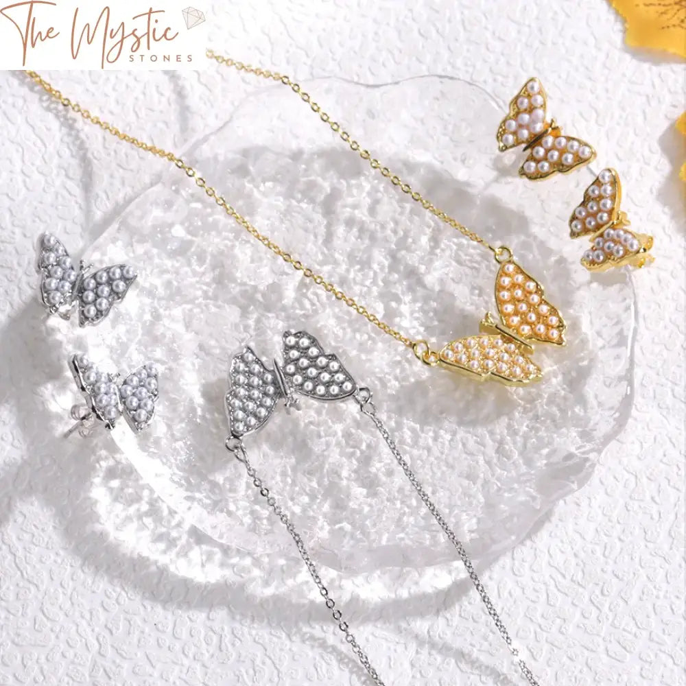 An elegant butterfly jewelry set is displayed, featuring a pair of gold-colored earrings and a matching necklace.