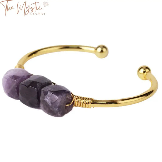 A collection of open cuff bangle bracelets featuring raw gemstones, including strawberry crystal, citrines, and amethysts.