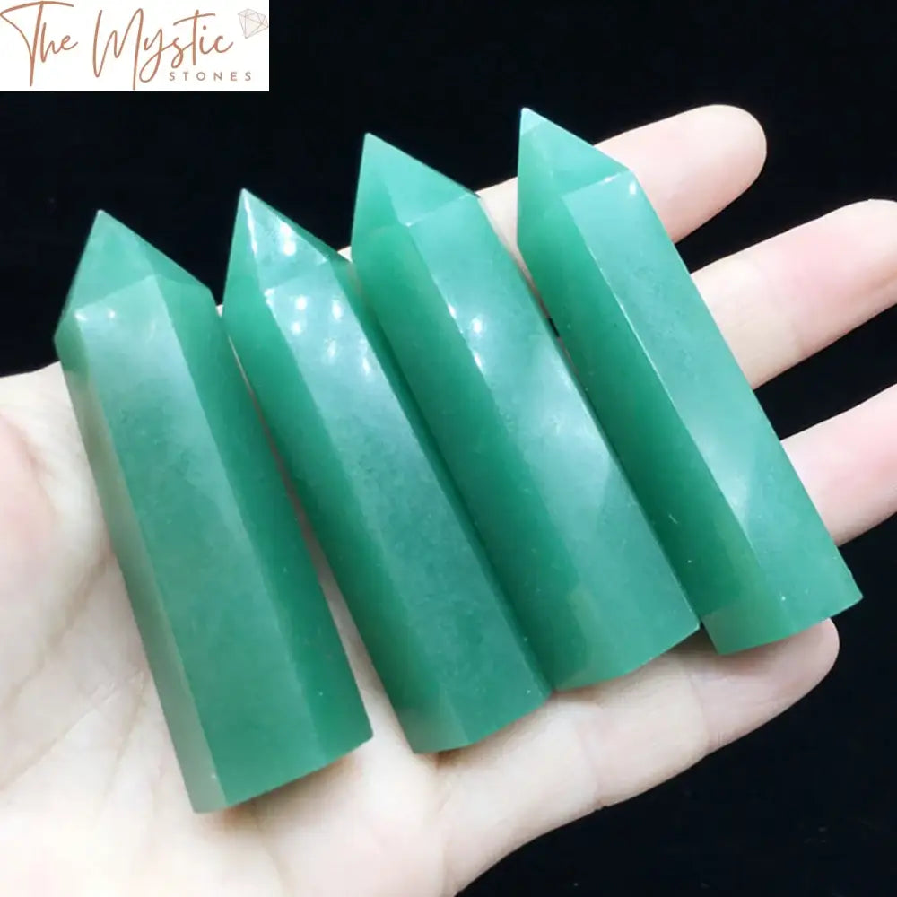 A natural Green Aventurine crystal point obelisk standing upright on a smooth surface.