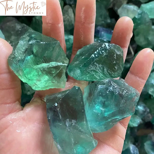 A collection of natural, raw green fluorite quartz crystals displayed on a flat surface.