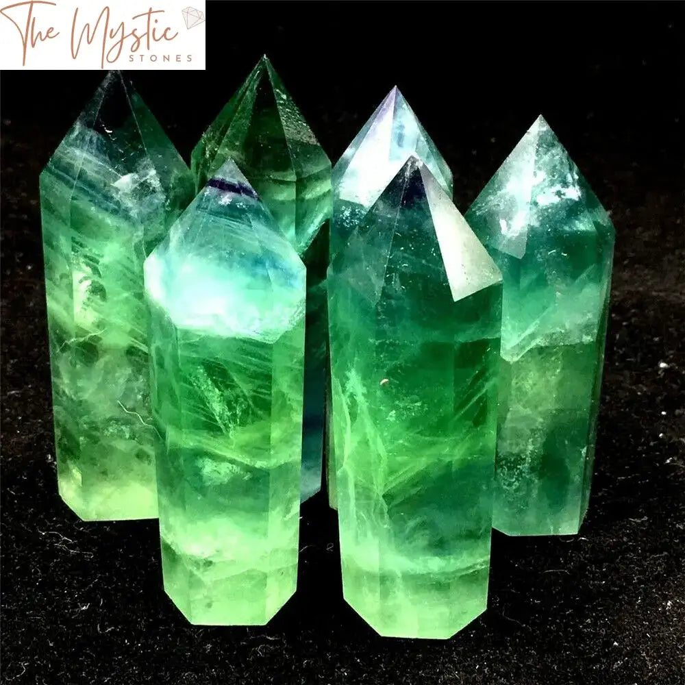 A vibrant green fluorite crystal point stands upright, showcasing its translucent, multifaceted surface.