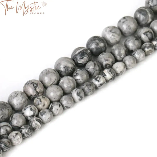 A collection of round, grey map-patterned natural stone beads in varying sizes (4mm, 6mm, 8mm, and 10mm) is spread out.