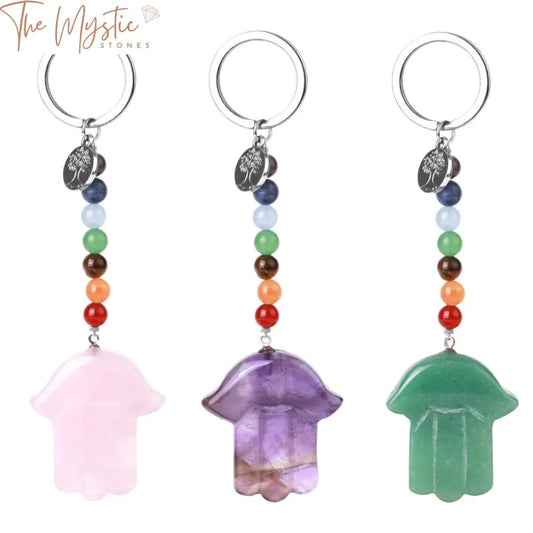 A luxury keychain featuring a Hamsa hand design adorned with seven chakra stones in varying colors.