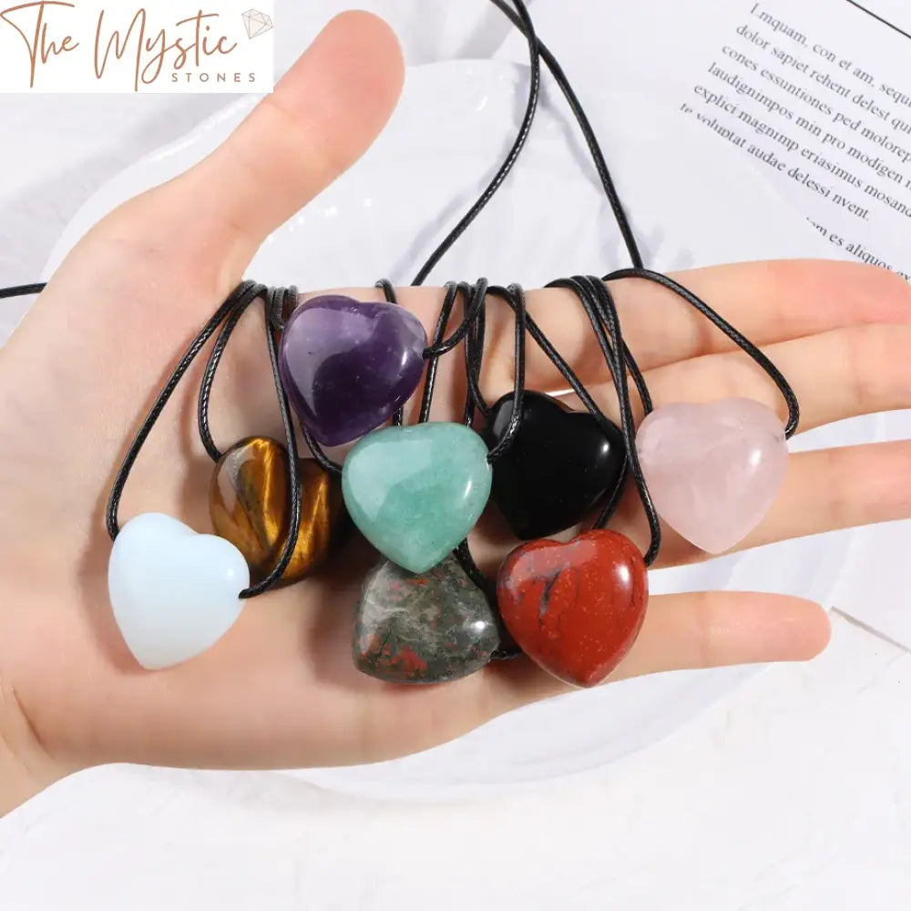 A collection of heart-shaped pendants made from natural stones, each featuring a unique type of crystal.