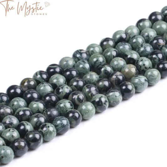 A collection of Kambaba Jasper beads, featuring a natural green hue with swirling patterns, arranged in a round shape.