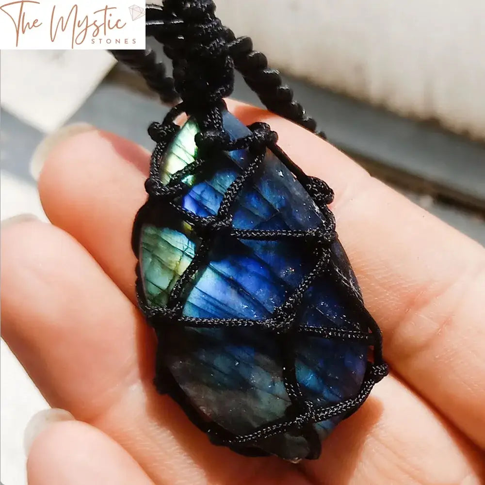 A polished labradorite moonstone with a mesmerizing blue sheen, intricately wrapped in a braided rope to create a pendant.