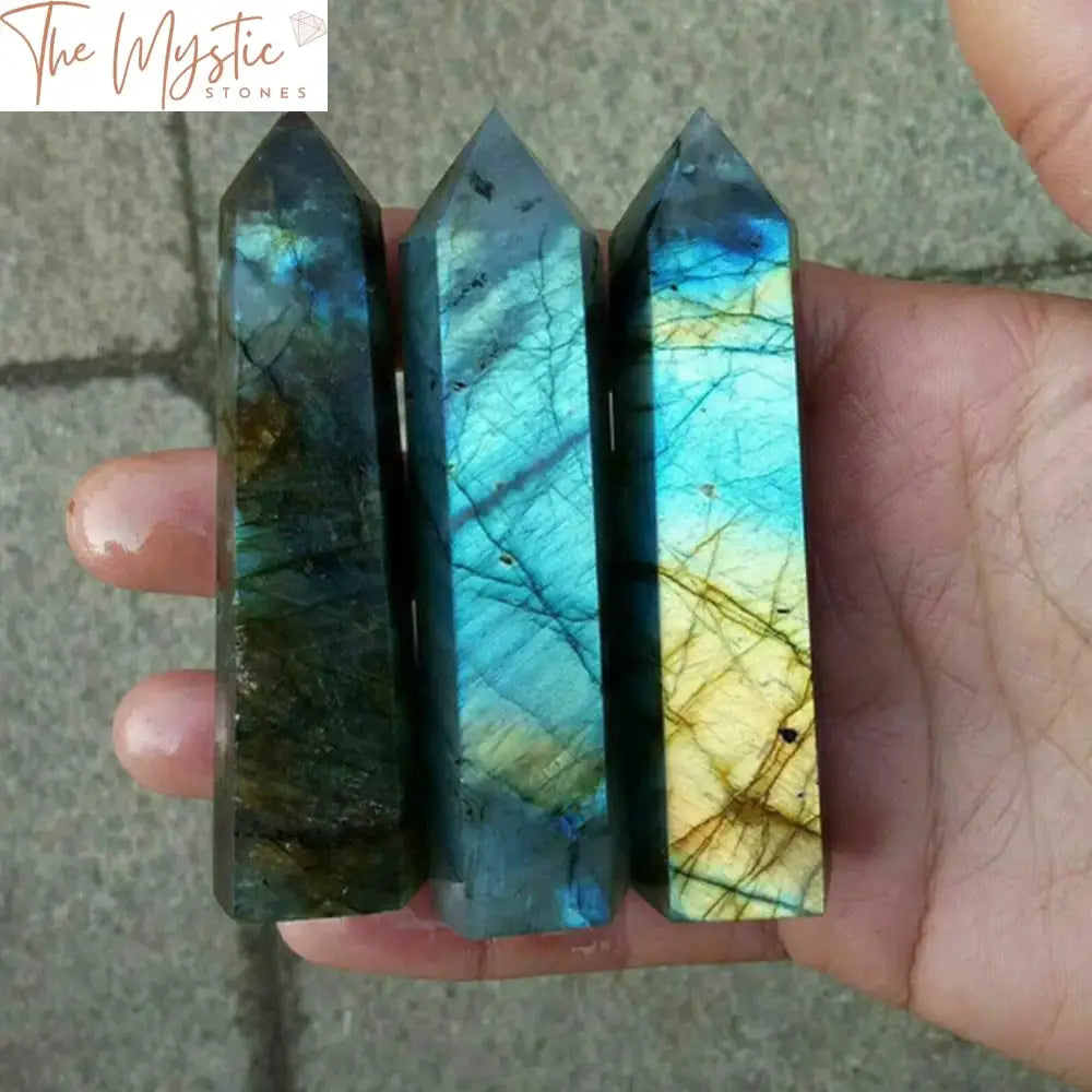 A collection of glossy, hexagonal prism-shaped crystal wands made from natural labradorite quartz.