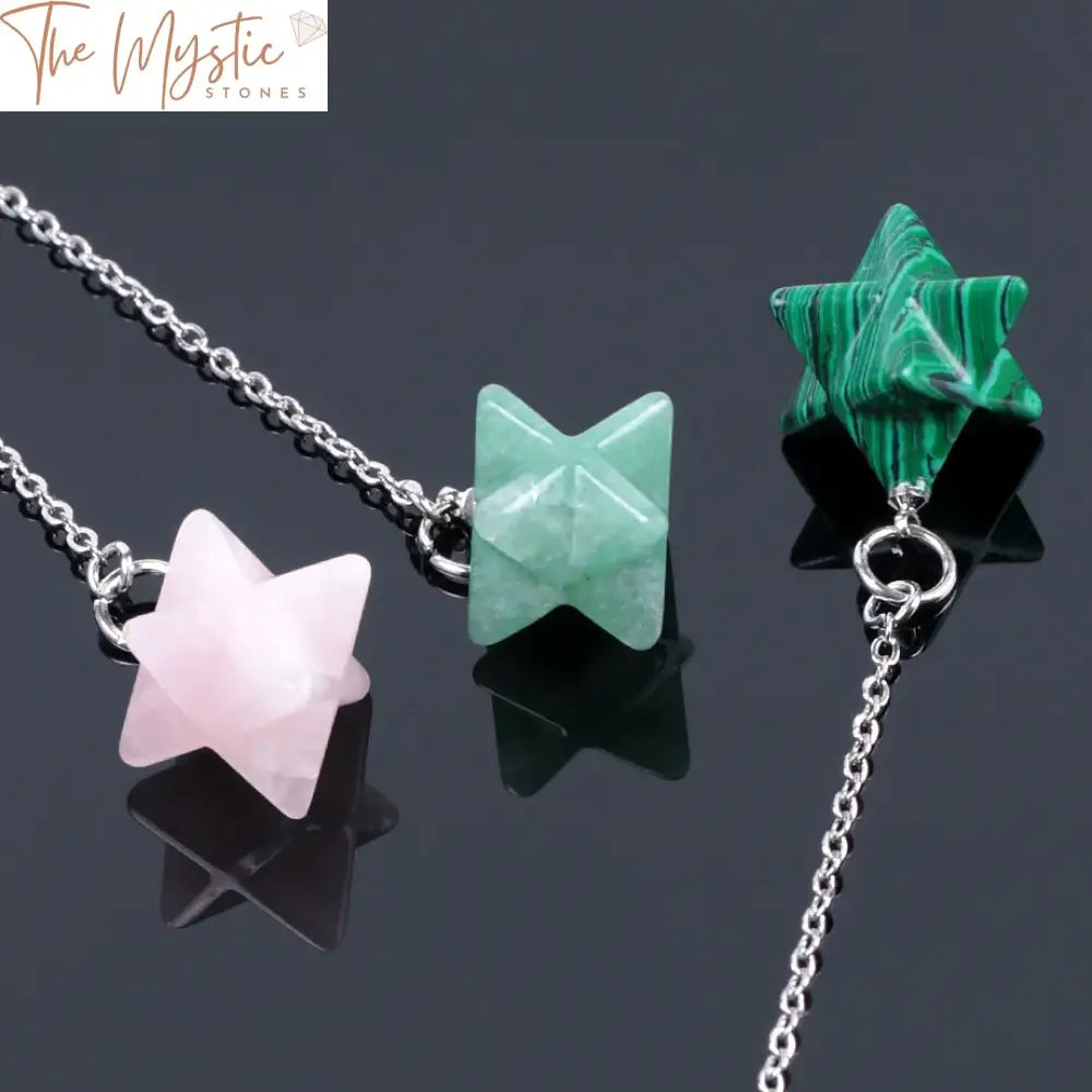 A collection of Merkabah-shaped pendulums crafted from natural gemstones, including pink crystal, lapis lazuli, and onyx.