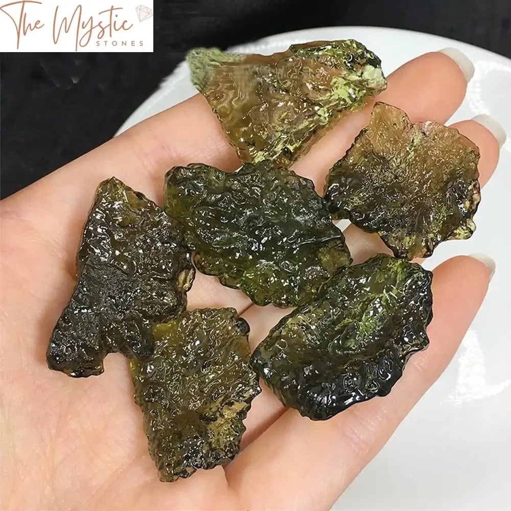 A close-up photo of a raw, irregularly shaped green gem known as Moldavite.