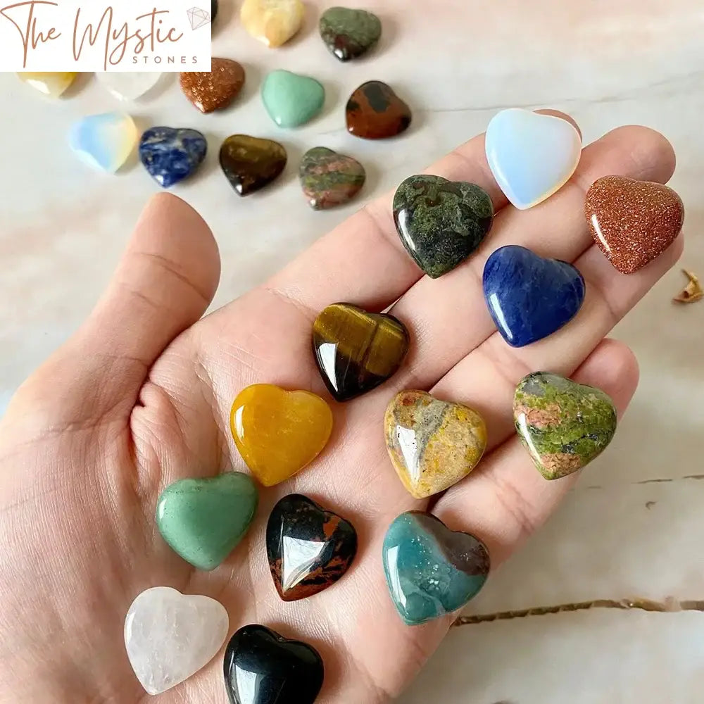 A collection of ten heart-shaped natural crystal quartz stones in various colors, arranged neatly on a light background.