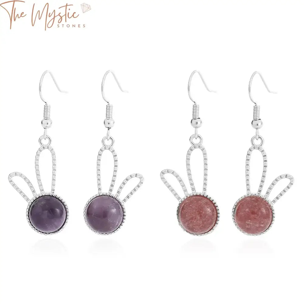 A pair of drop earrings featuring a natural stone cabochon bead with a translucent crystal.