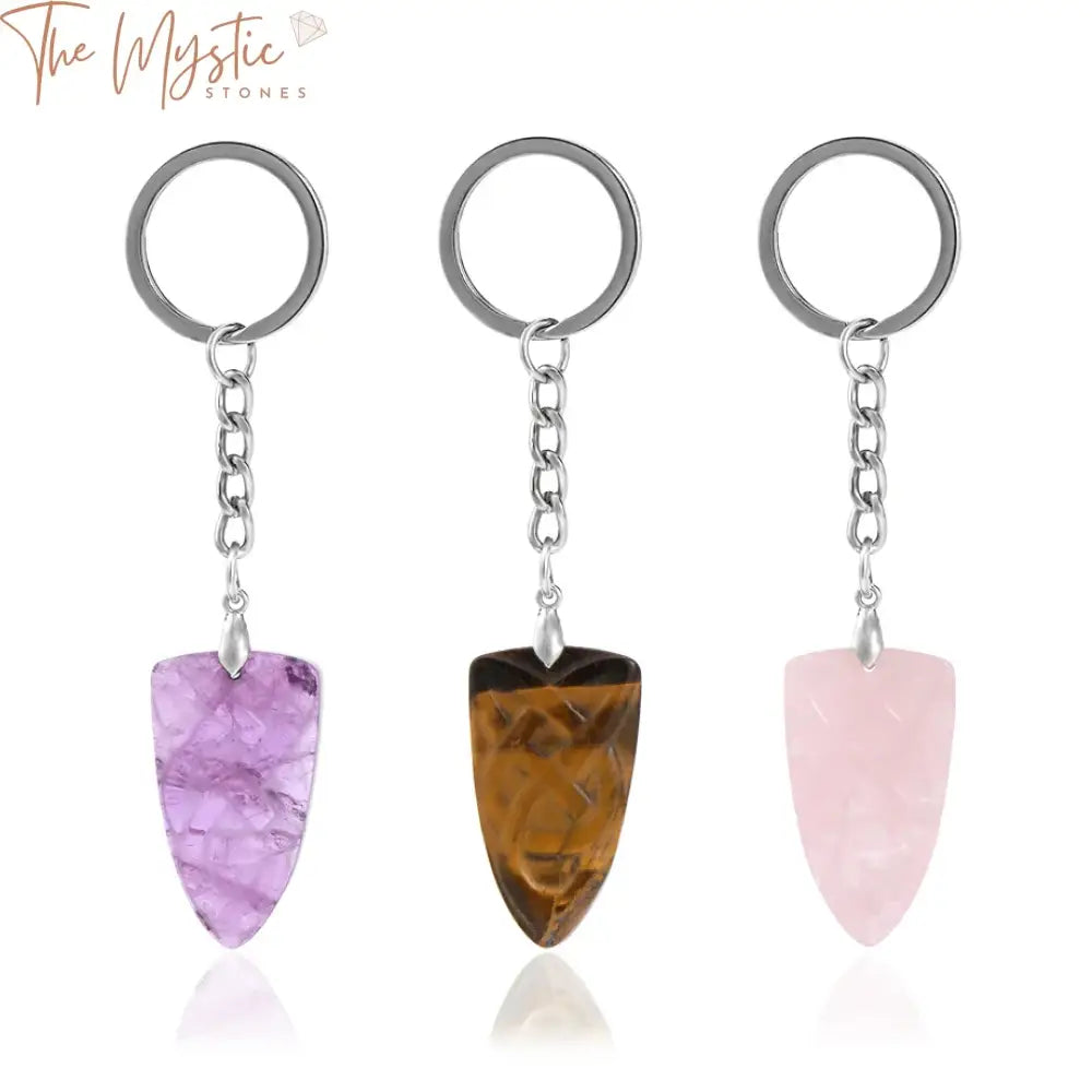 A natural stone keychain featuring a handmade carved shield-shaped pink crystal pendant.