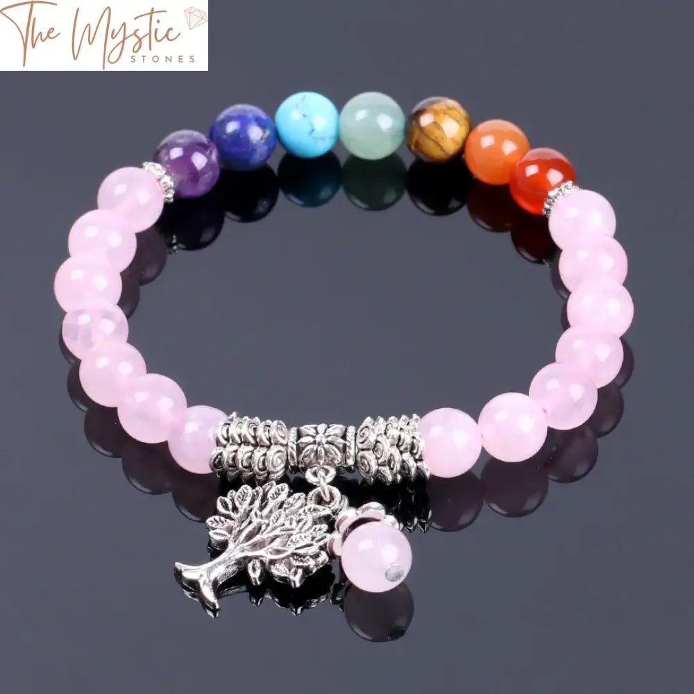 A beaded bracelet featuring a tree pendant made of natural pink crystal quartz and seven chakra gemstones.