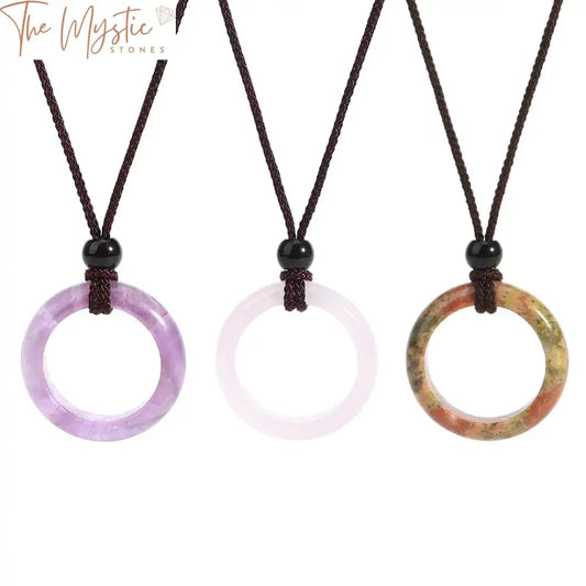 A round pink quartz stone pendant necklace with a polished, smooth surface hangs from a delicate chain.