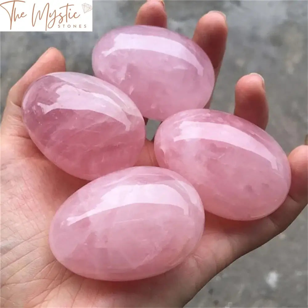 A smooth, polished sphere made from natural pink rose quartz crystal, resting on a small stand.