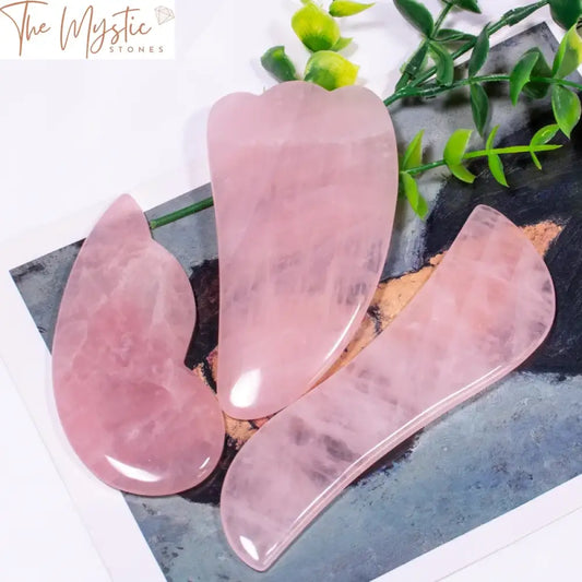 A polished pink rose quartz gua sha board with smooth, curved edges designed for facial and body massage.