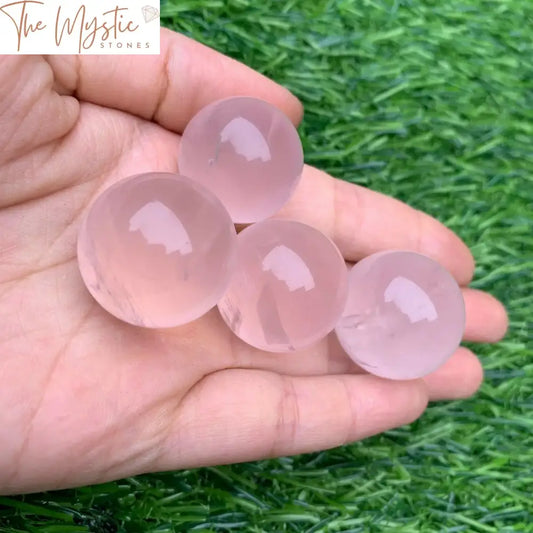 A single, polished pink rose quartz crystal sphere is displayed against a plain background.