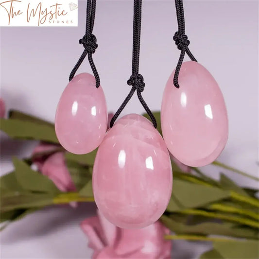 A set of natural pink rose quartz items, including three yoni jade eggs of varying sizes and a sleek, polished massage stick.