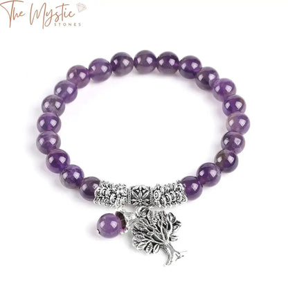 A collection of purple crystal bracelets displayed on a white surface, featuring a prominent Tree of Life charm.