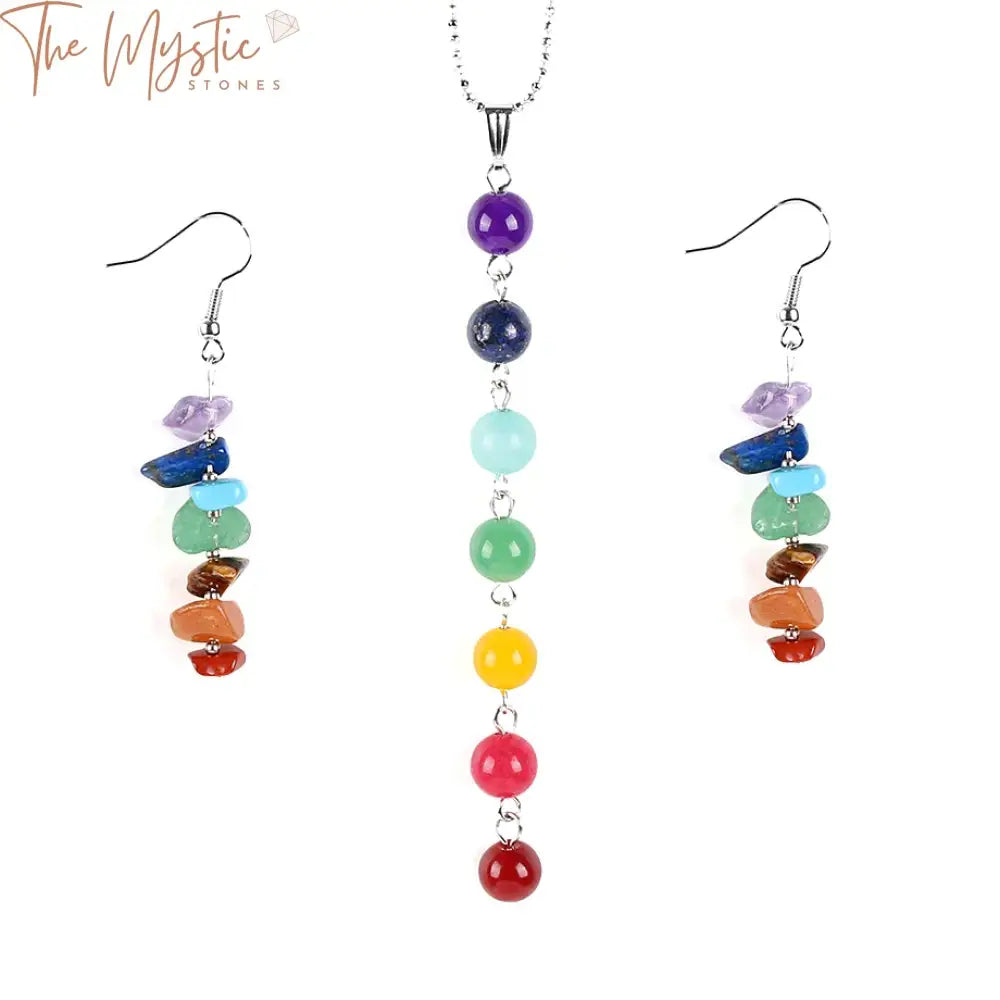 A set of 7 chakra-themed jewelry featuring a necklace and earrings made with natural gemstone chips in various colors.