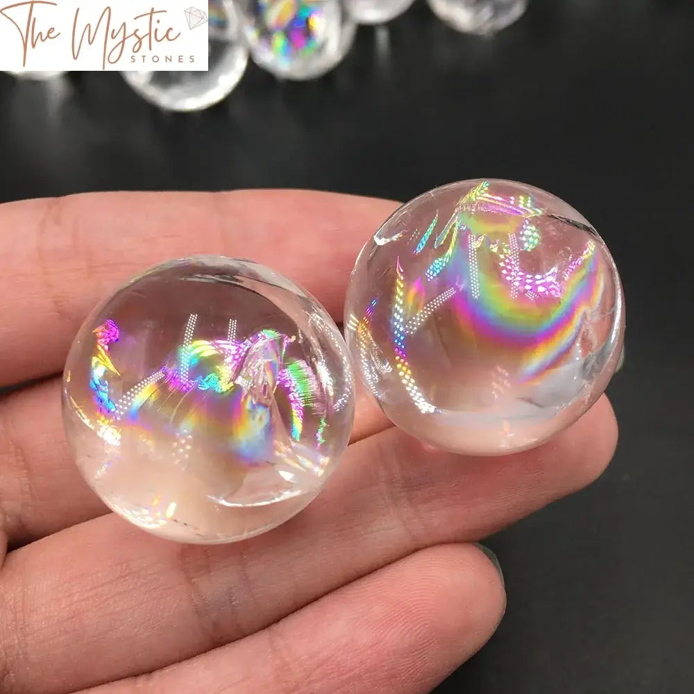 A clear rainbow quartz ball sits on a decorative base, exhibiting a mesmerizing array of shimmering colors and reflections.